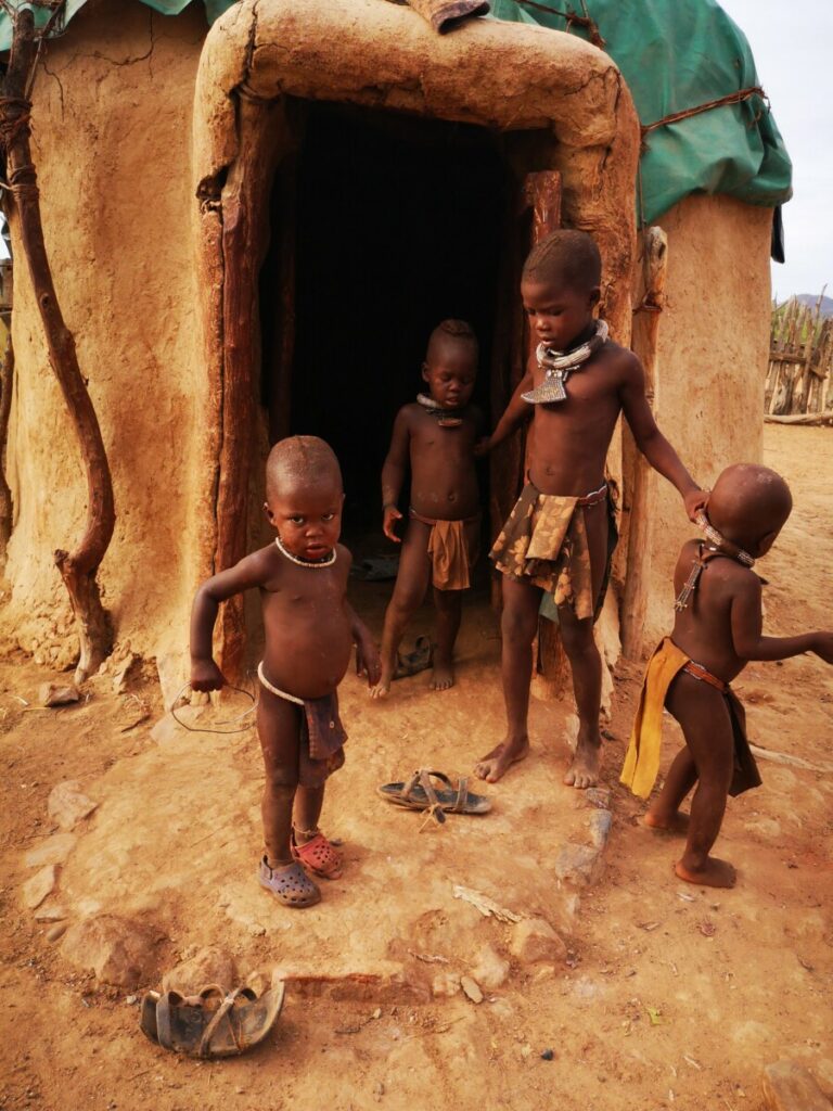Kinderen spelen voor de ingang van een himba hut Kinderen spelen voor de ingang van een himba hut